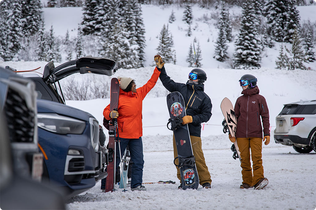 skier and snowboarder high five in parking lot
