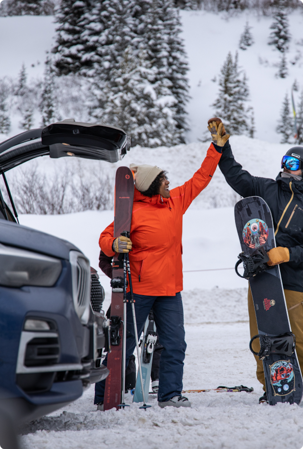 Skier and Snowboarder high five in parking lot